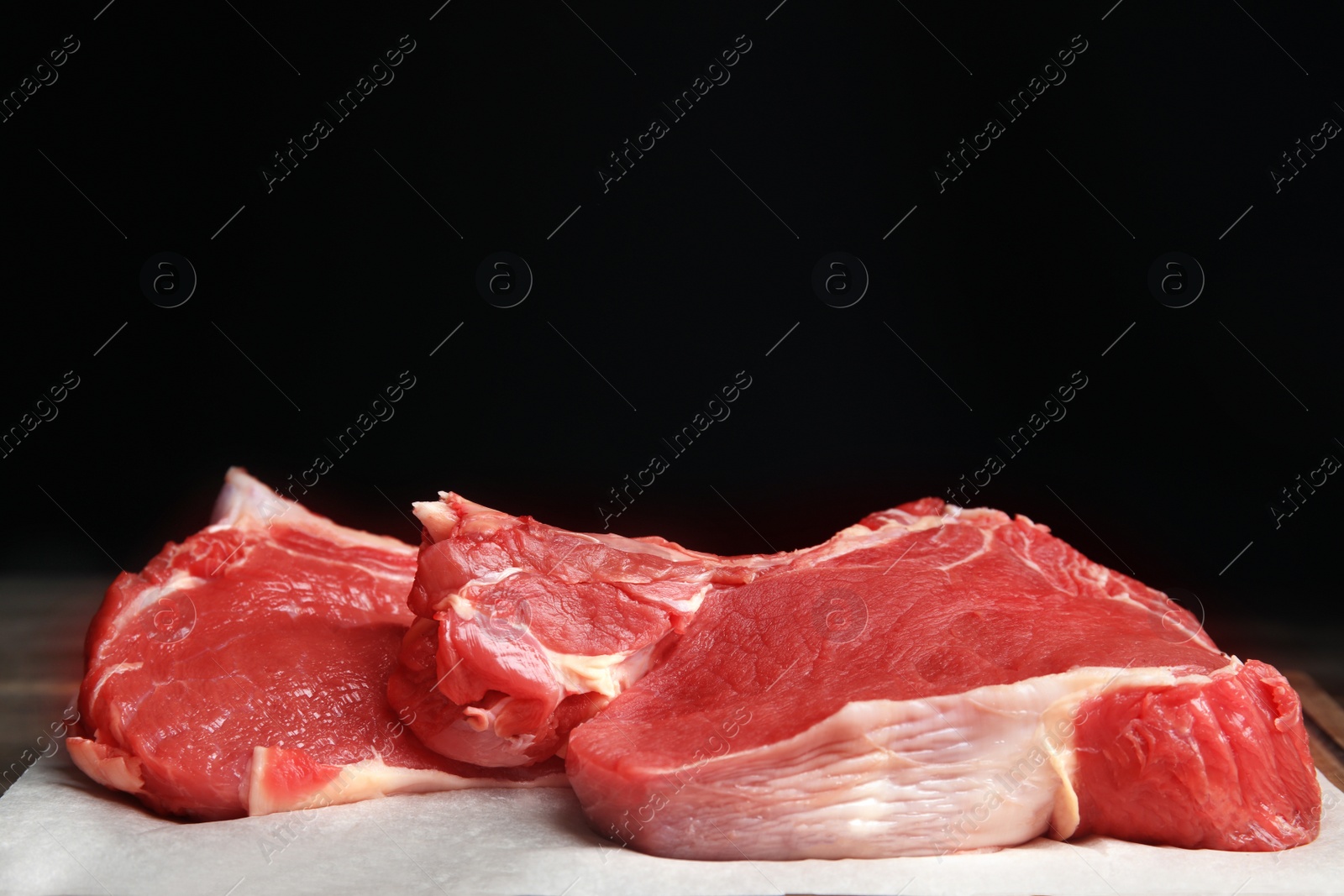 Photo of Fresh raw beef cut on table against black background, closeup