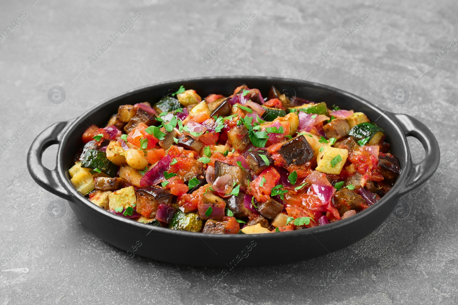 Photo of Dish with tasty ratatouille on grey textured table