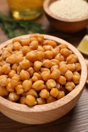 Photo of Delicious chickpeas on wooden table, closeup. Hummus ingredient