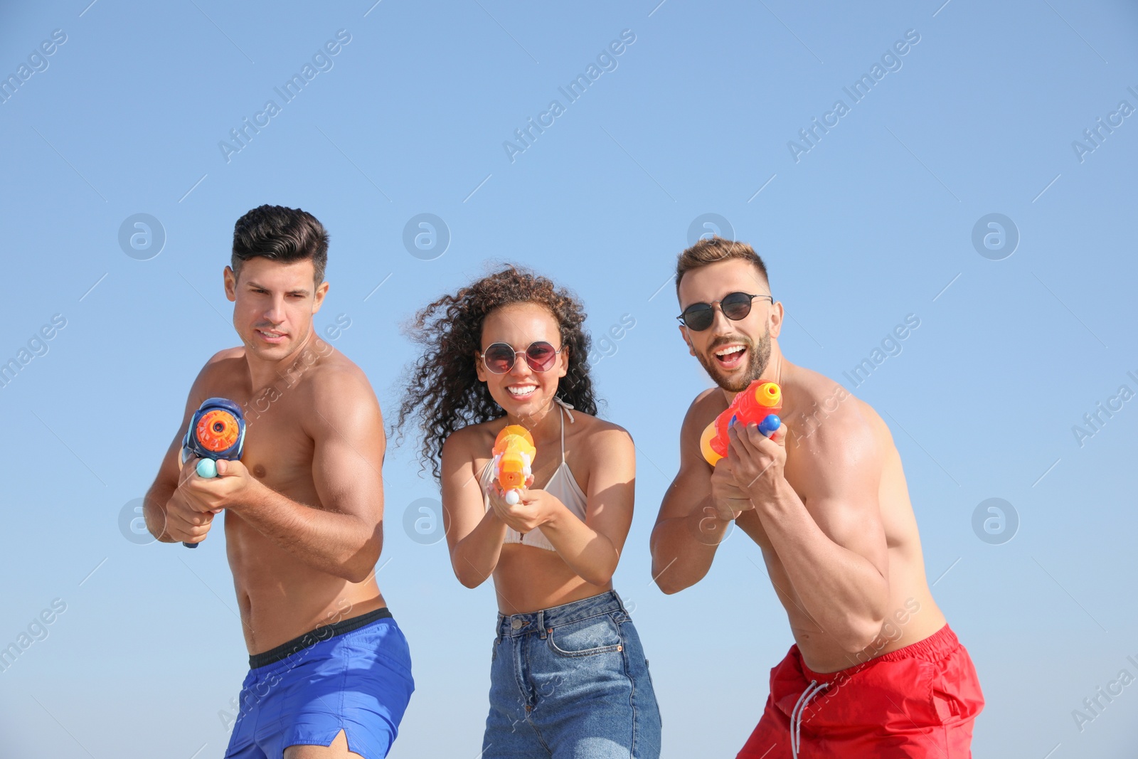 Photo of Friends with water guns having fun against blue sky