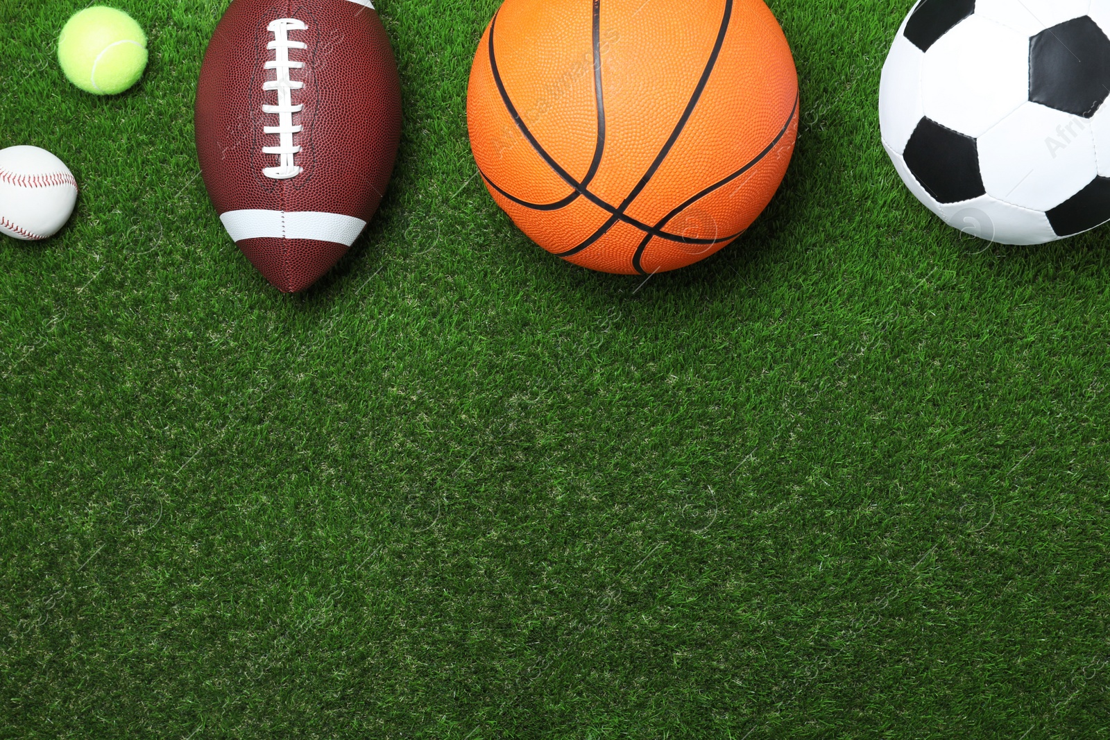 Photo of Set of different sport balls on green grass, flat lay. Space for text