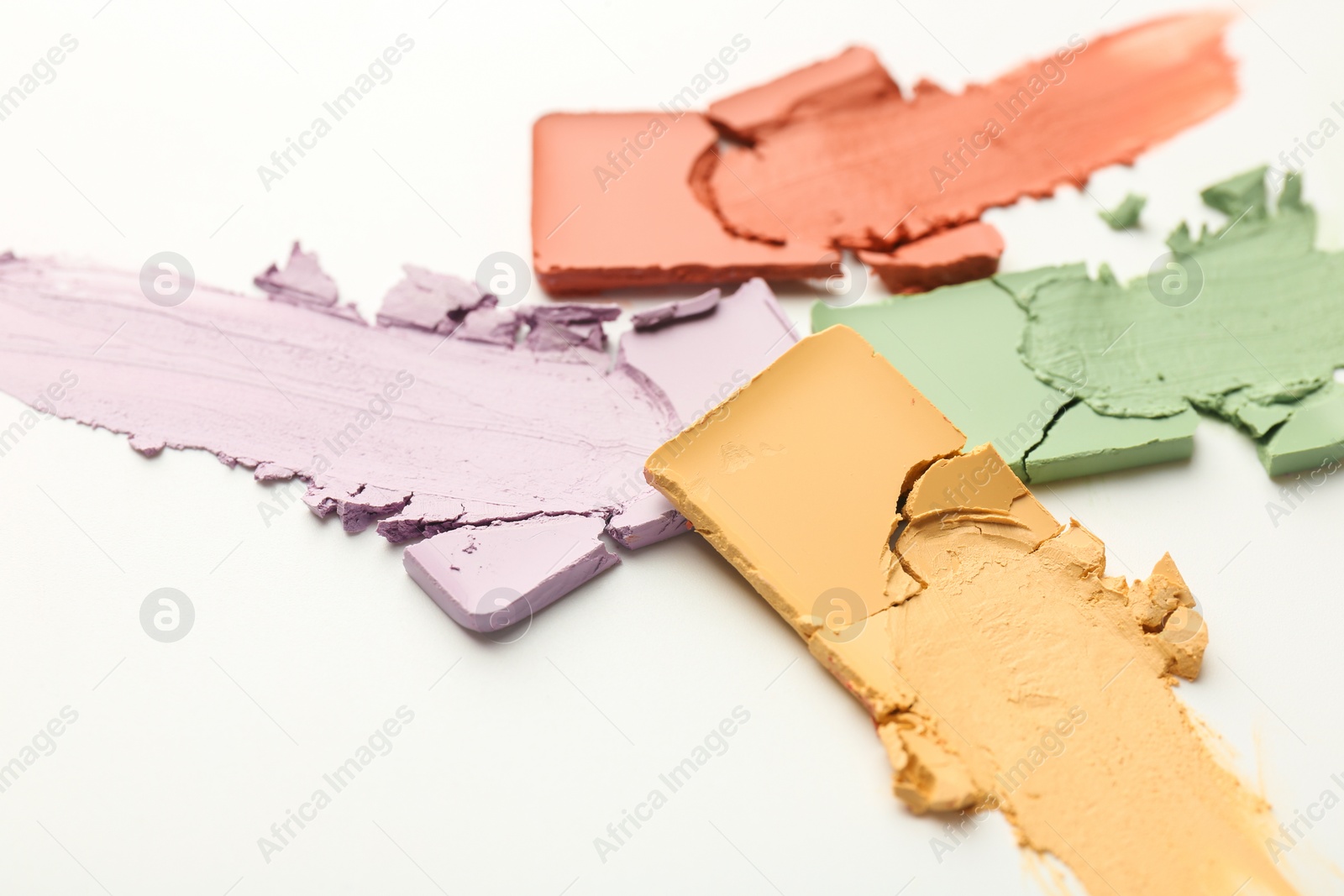 Photo of Samples of different color correcting concealers on white background, closeup