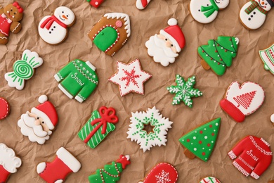 Photo of Different Christmas gingerbread cookies on crumpled parchment, flat lay