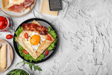 Photo of Delicious crepe with egg served on light gray textured table, flat lay with space for text. Breton galette