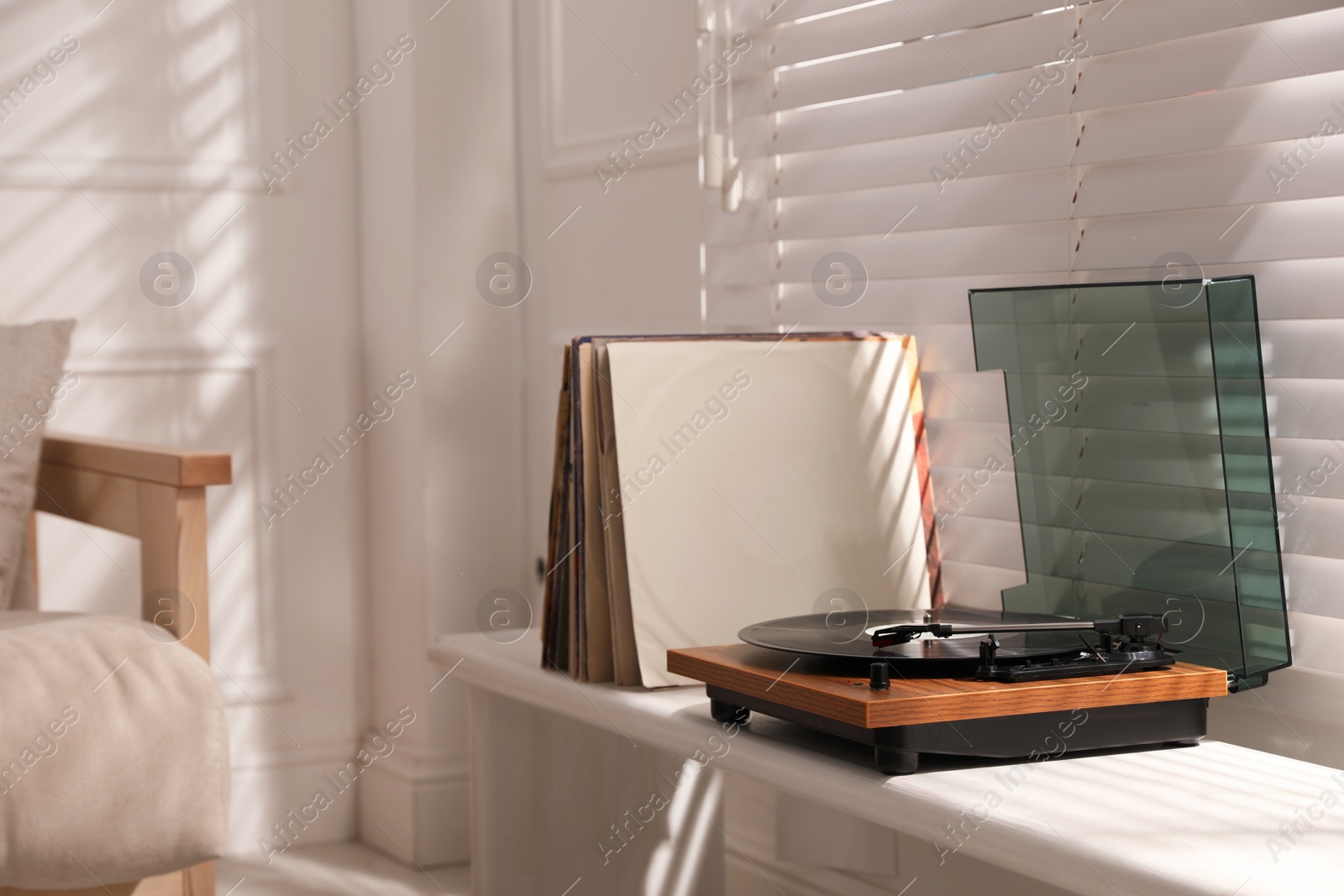 Photo of Stylish turntable with vinyl discs on windowsill in room. Space for text