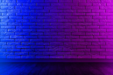 Room with brick wall and wooden floor in neon lights