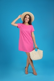 Young woman with stylish straw bag on light blue background