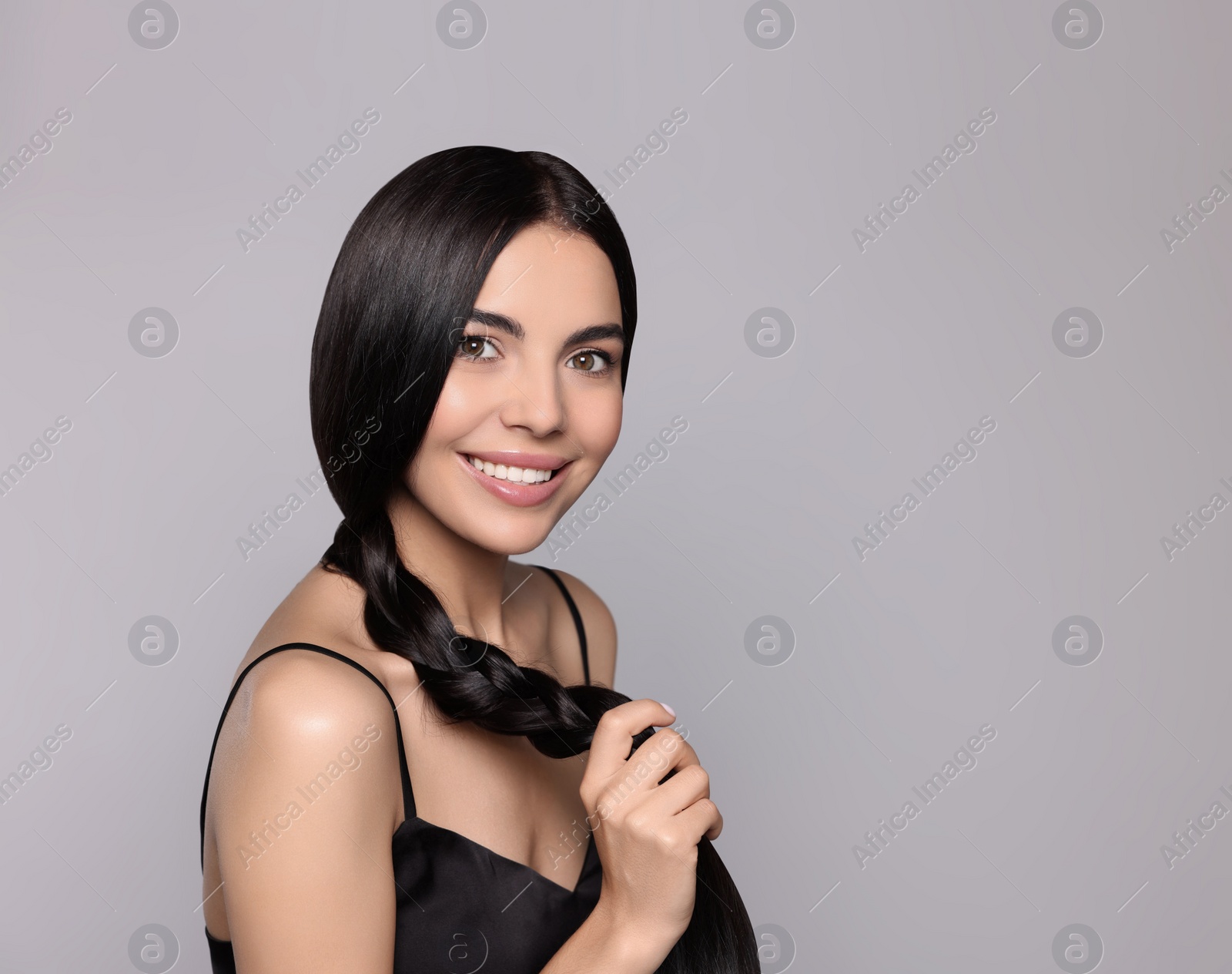 Photo of Portrait of beautiful young woman with healthy strong hair on light grey background, space for text