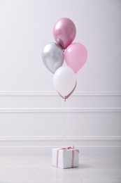 Photo of One gift box and balloons near white wall in room