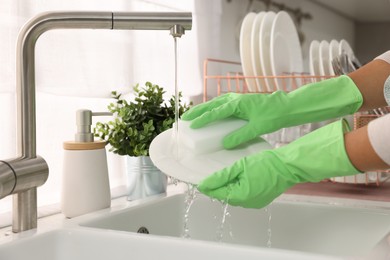 Photo of Woman washing plate at sink in kitchen, closeup