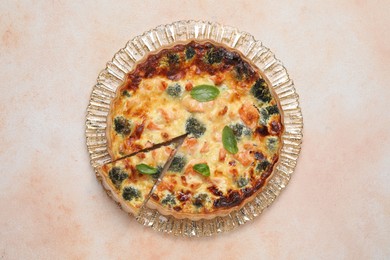 Delicious homemade quiche with salmon and broccoli on beige table, top view
