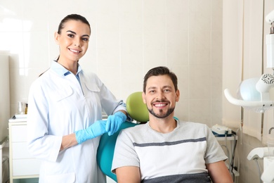 Photo of Professional dentist and happy patient in modern clinic