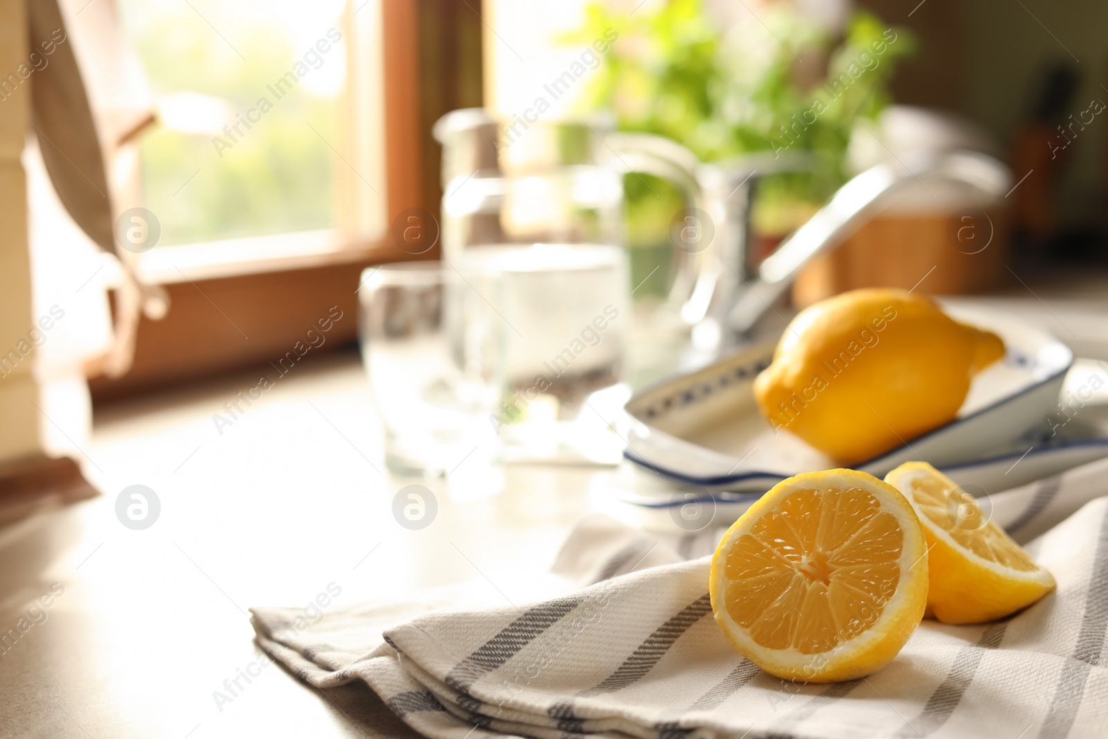 Photo of Halves of fresh ripe lemon on countertop in kitchen, space for text