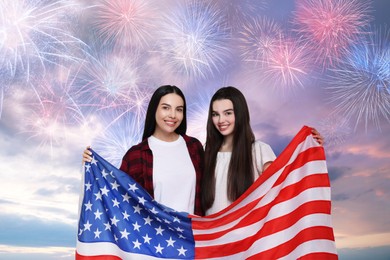 Image of 4th of July - Independence day of America. Happy mother and daughter holding national flag of United States against sky with fireworks