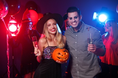 Happy couple enjoying Halloween party on dark background