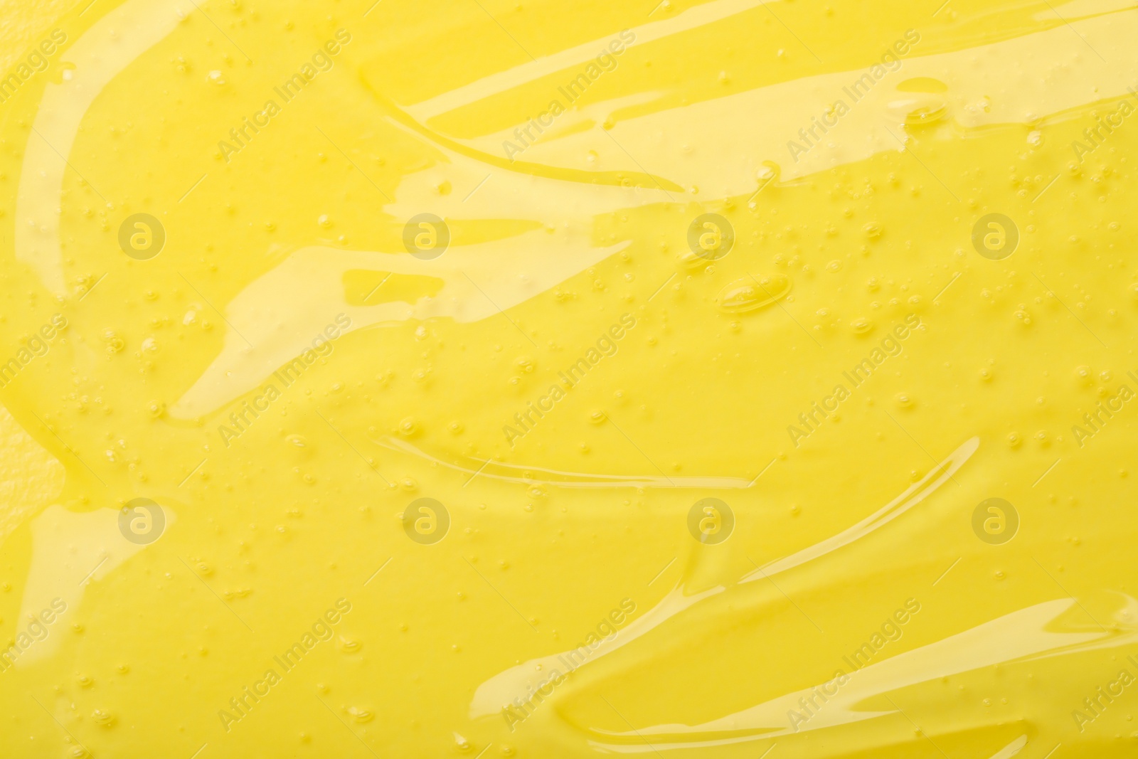 Photo of Pure transparent cosmetic gel on yellow background, closeup