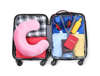 Photo of Soft travel pillow, headphones, passports and other items in open suitcase isolated on white, top view