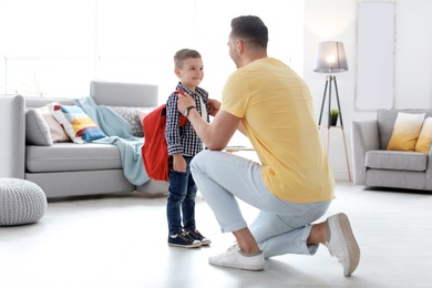 Young man helping his little child get ready for school at home