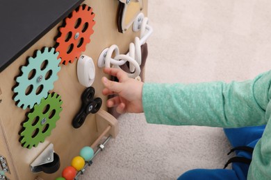 Little child playing with busy board house on floor, closeup