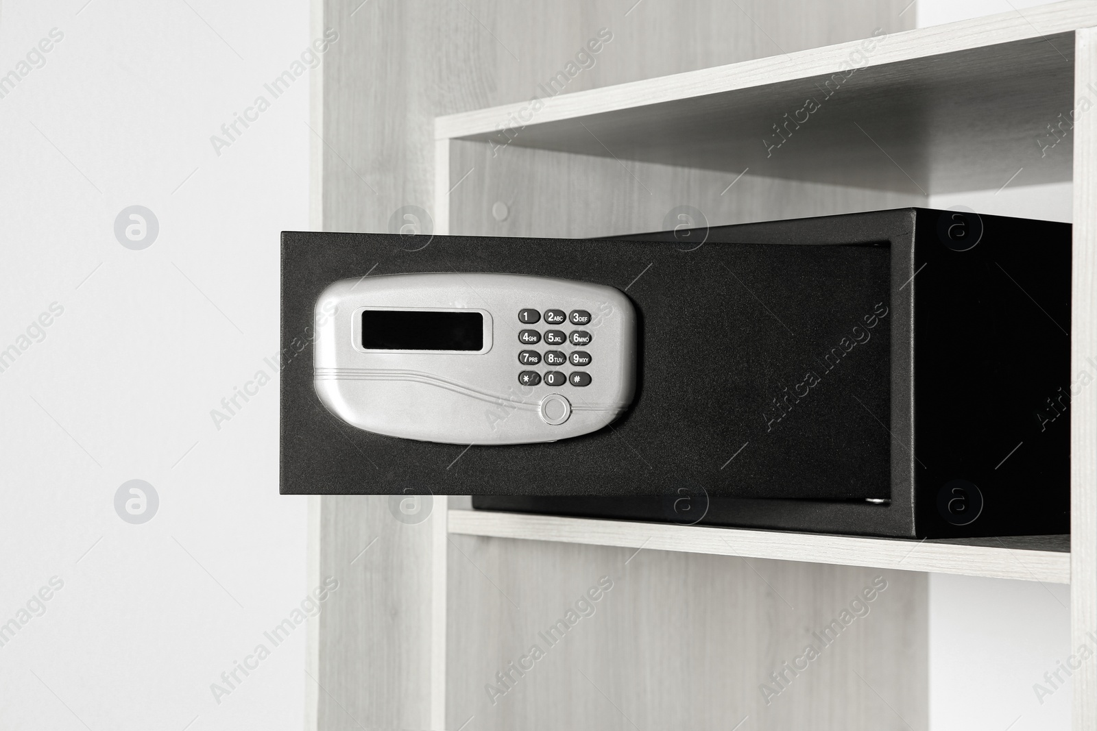 Photo of Black steel safe with electronic lock in wooden closet