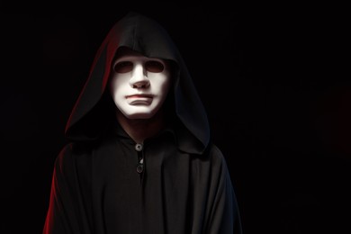 Photo of Theatrical performance. Man in mantle and plastic mask on black background, space for text