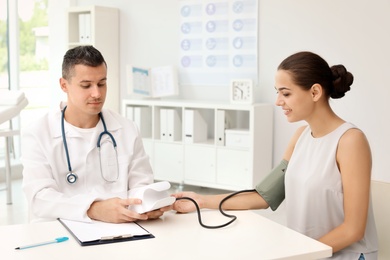 Doctor checking patient's blood pressure in hospital