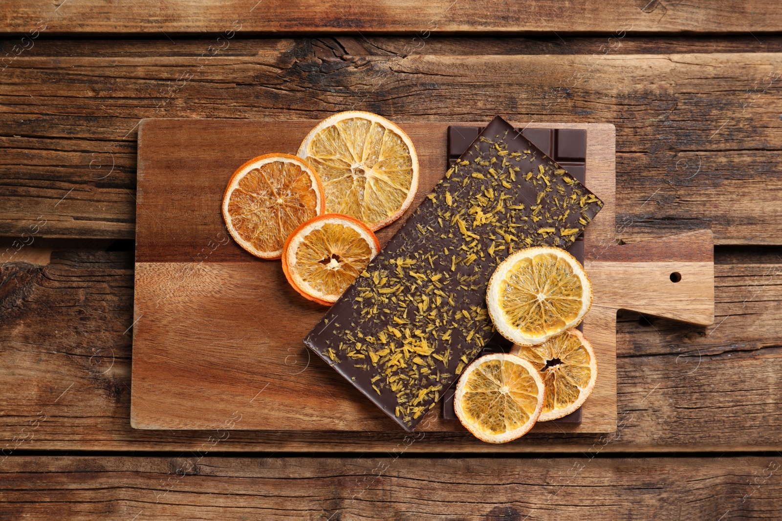 Photo of Board and chocolate bars with freeze dried orange on wooden table, top view