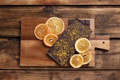 Photo of Board and chocolate bars with freeze dried orange on wooden table, top view