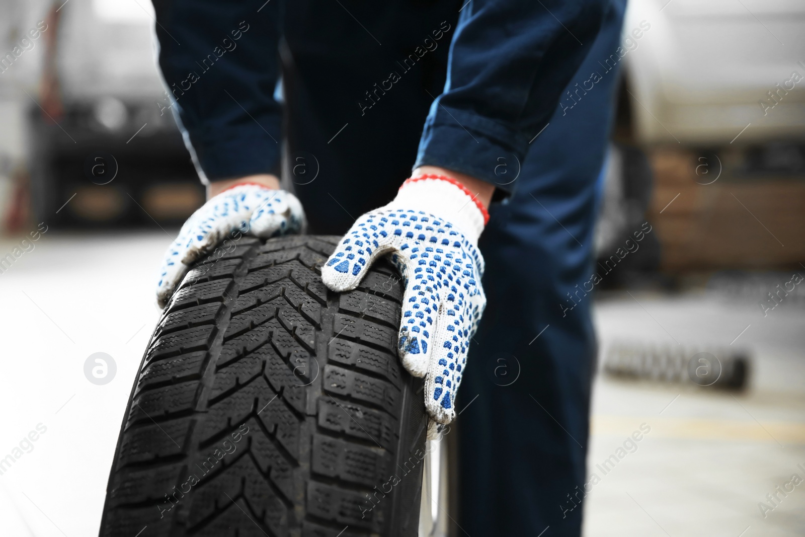 Photo of Mechanic with car tire in service center, closeup