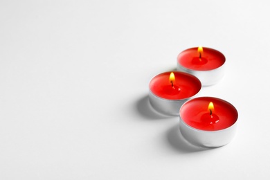 Photo of Colorful wax candles burning on white background