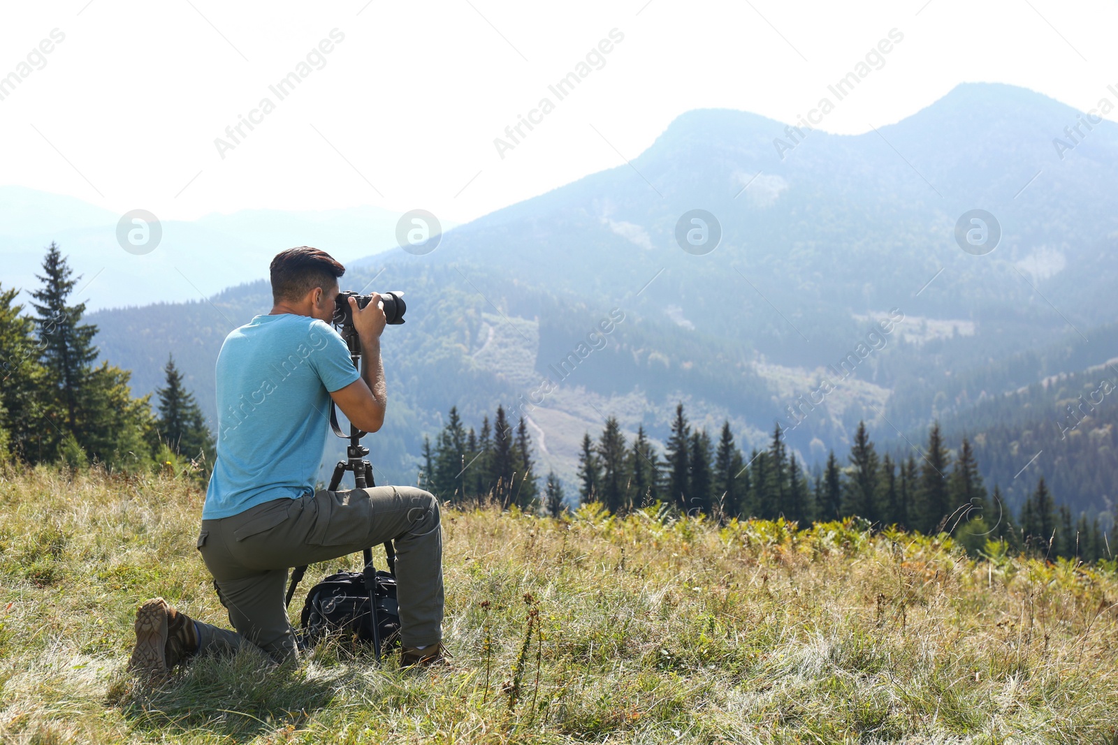 Photo of Man taking photo of mountain landscape with modern camera on tripod outdoors