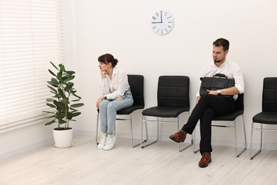 Photo of Man and woman waiting for job interview indoors