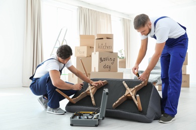 Male movers assembling sofa in new house