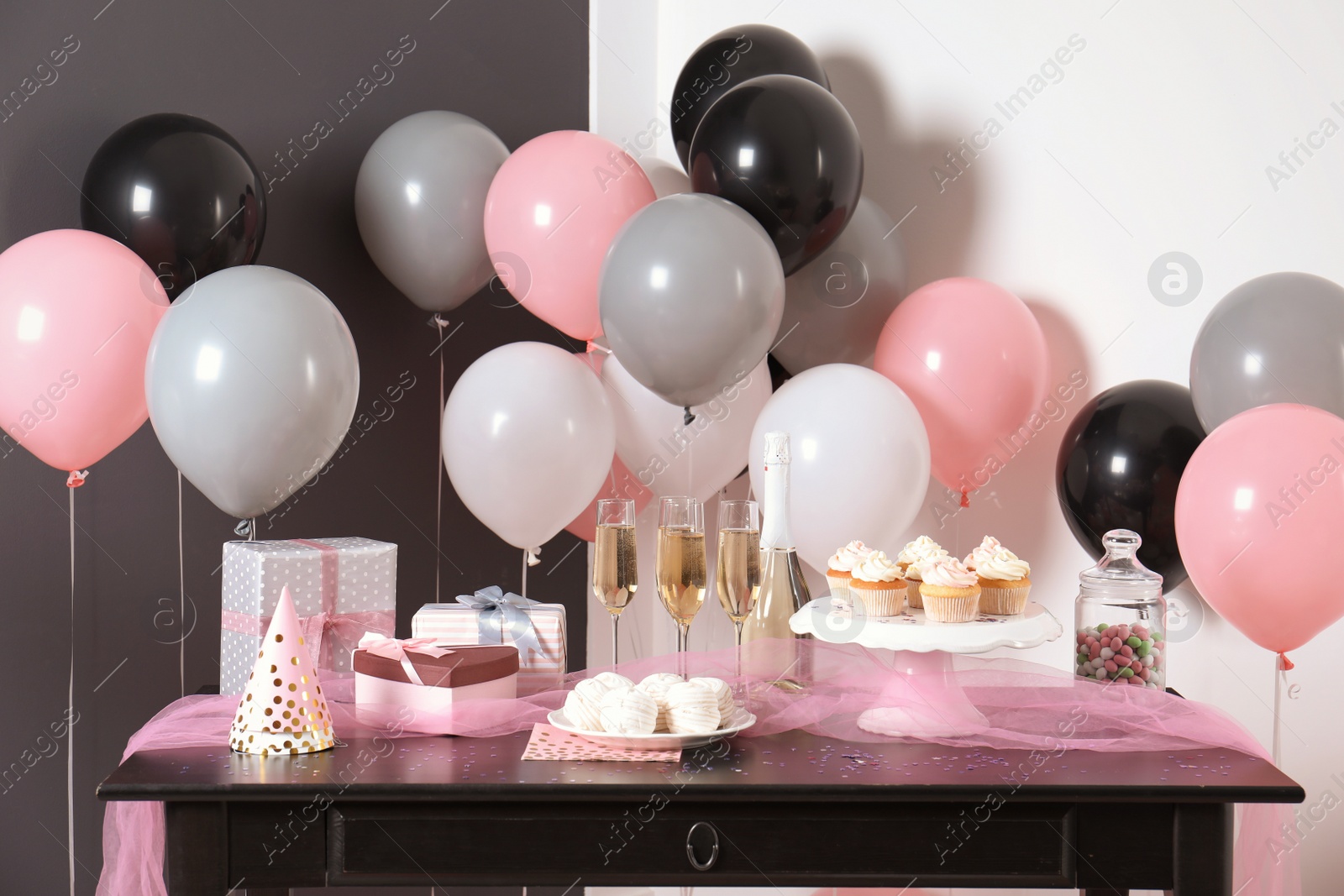 Photo of Party treats and items on table in room decorated with balloons