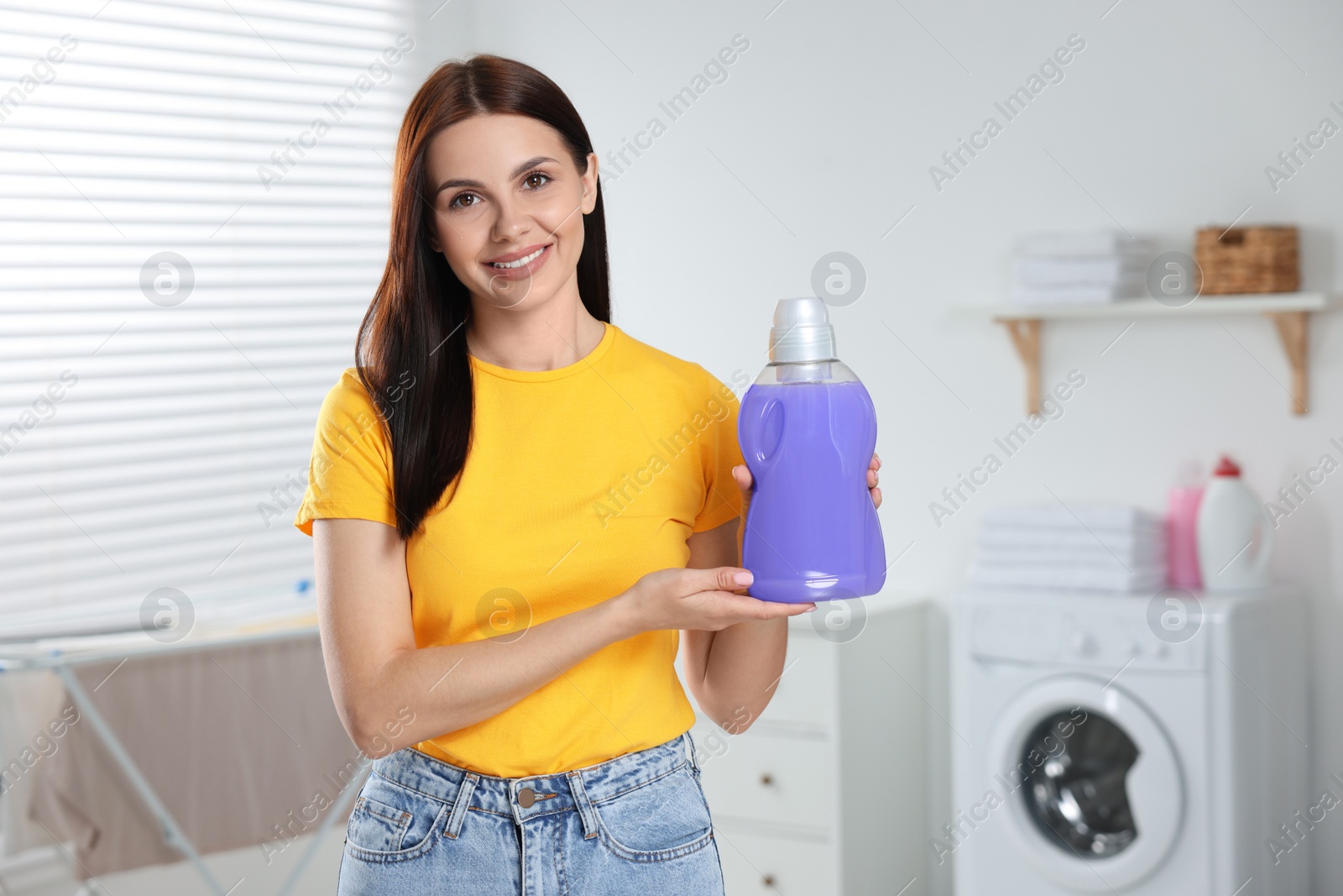 Photo of Woman showing fabric softener in bathroom, space for text