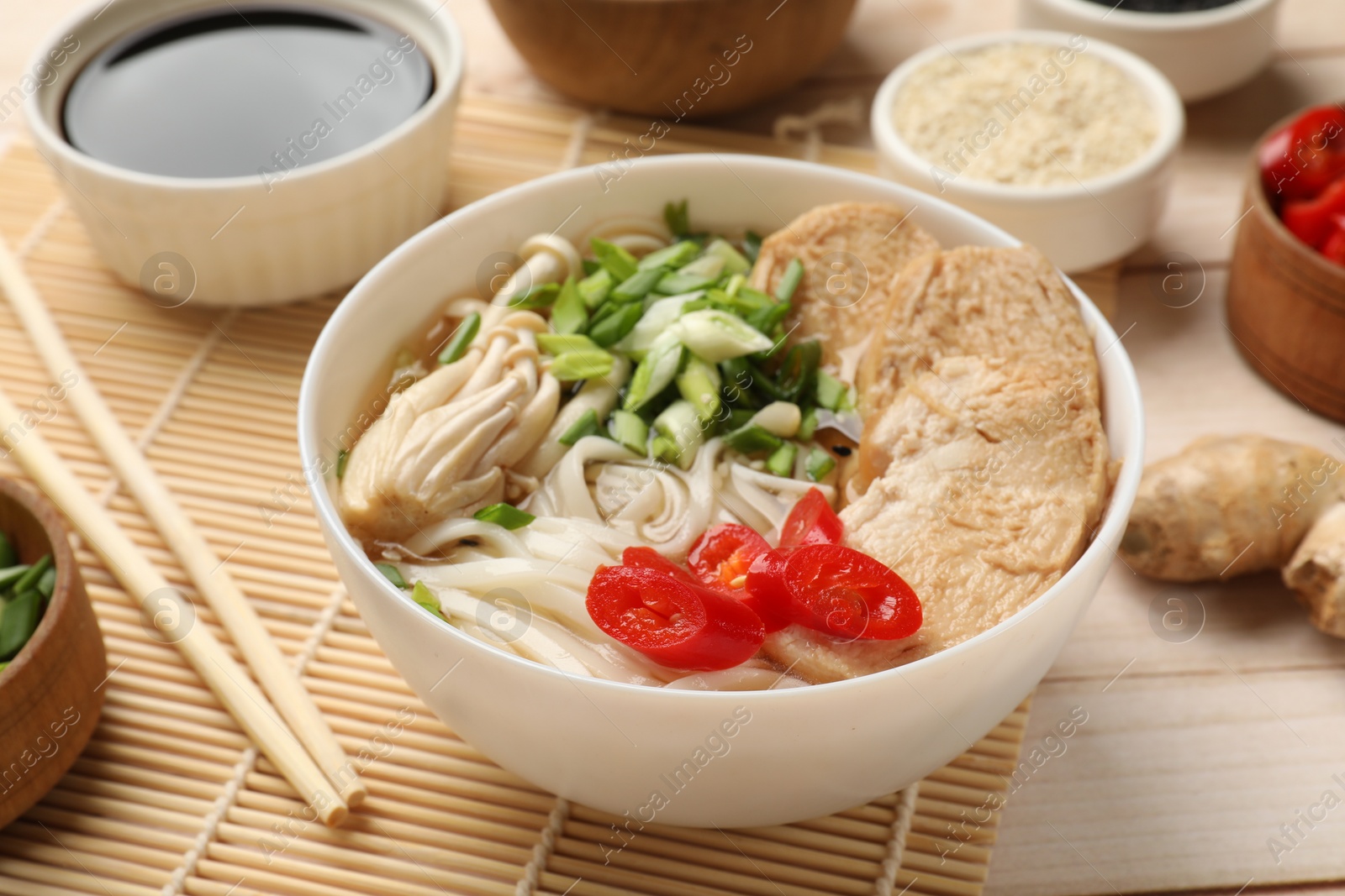 Photo of Delicious ramen with meat and ingredients on white wooden table, closeup. Noodle soup