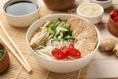 Delicious ramen with meat and ingredients on white wooden table, closeup. Noodle soup