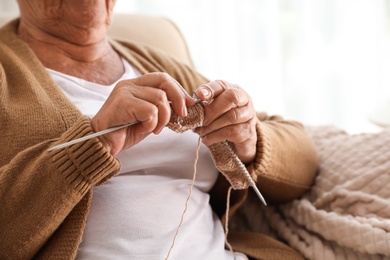 Photo of Elderly woman knitting at home, closeup. Creative hobby