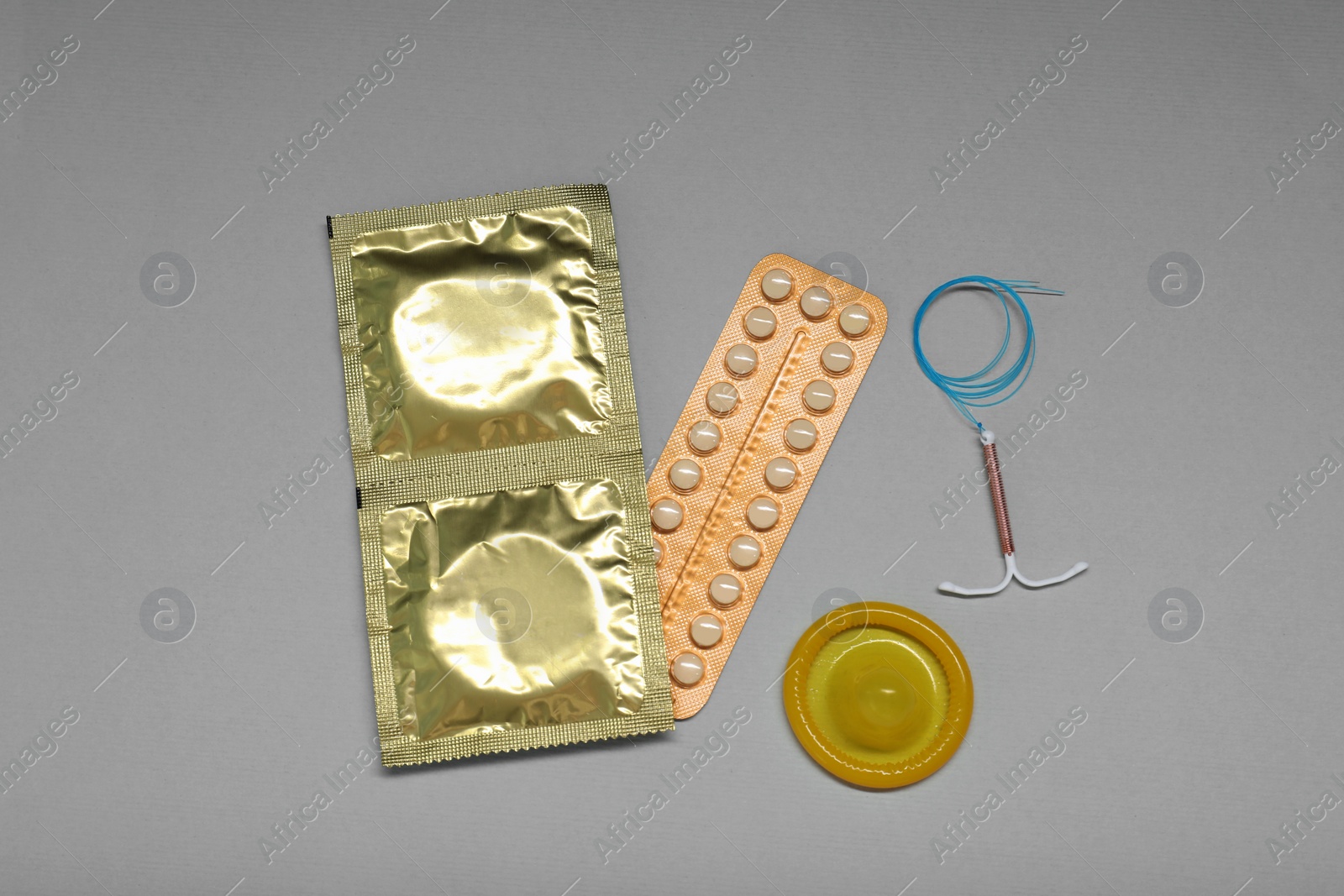 Photo of Contraceptive pills, condoms and intrauterine device on light grey background, flat lay. Different birth control methods
