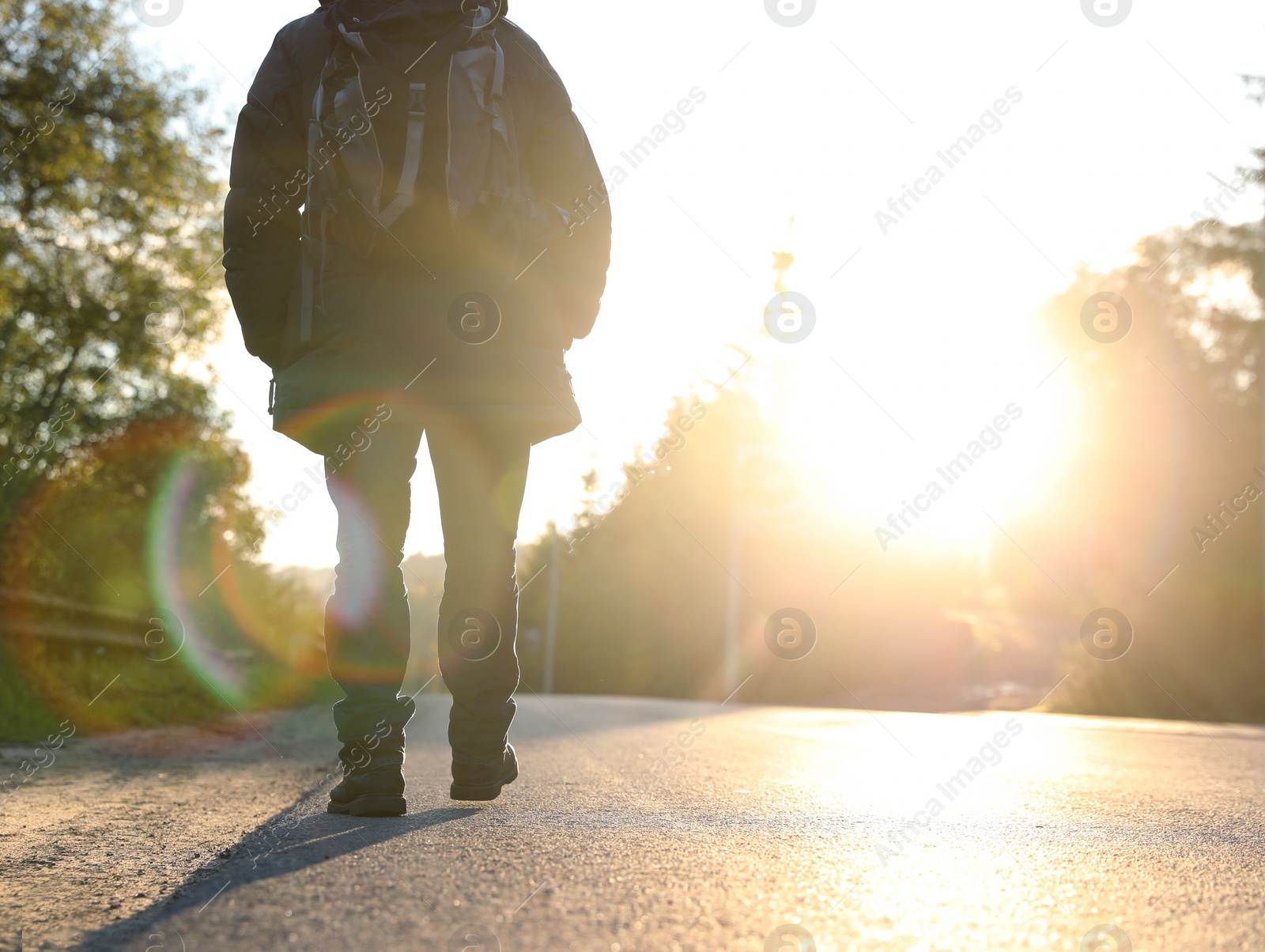 Photo of Man walking along road on sunny day, back view. Space for text