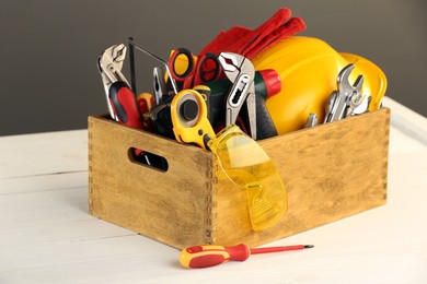 Photo of Wooden box with different tools for repair and protective glasses on white table