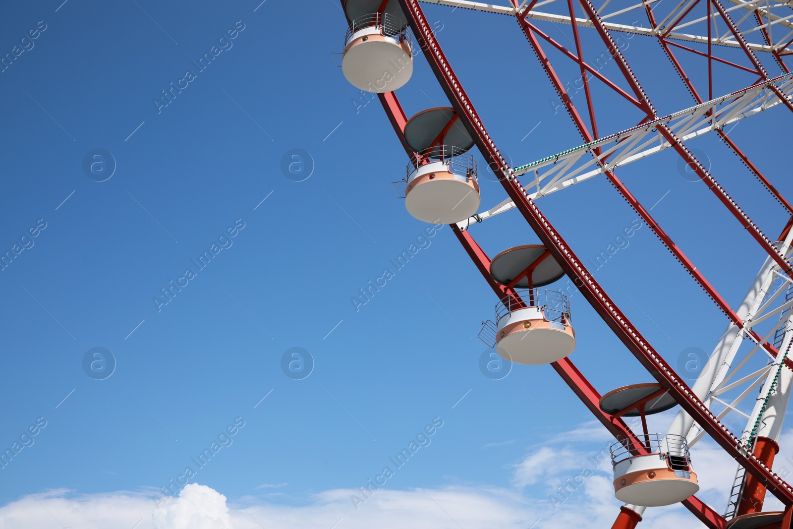 Photo of Beautiful large Ferris wheel against blue sky, low angle view