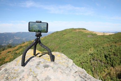 Photo of Taking video with modern phone on tripod in mountains