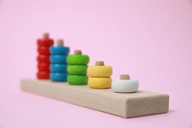 Stacking and counting game wooden pieces on pink background. Educational toy for motor skills development