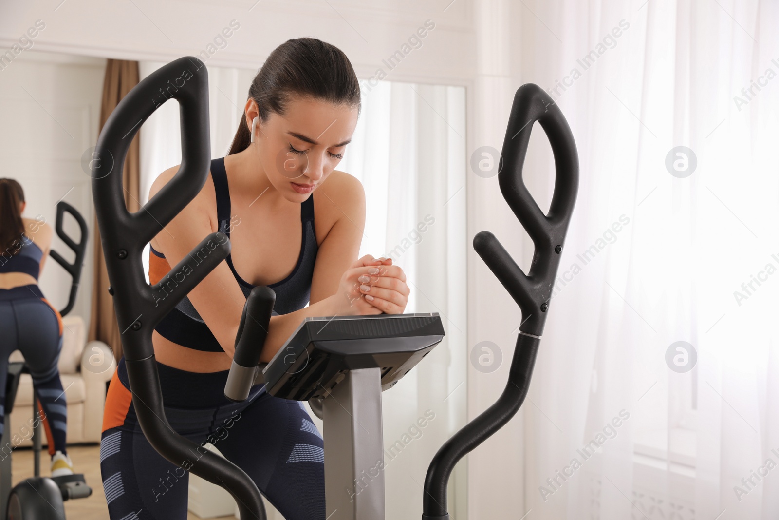 Photo of Tired woman after training on modern elliptical machine at home