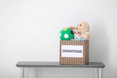 Donation box with toys on table against light background