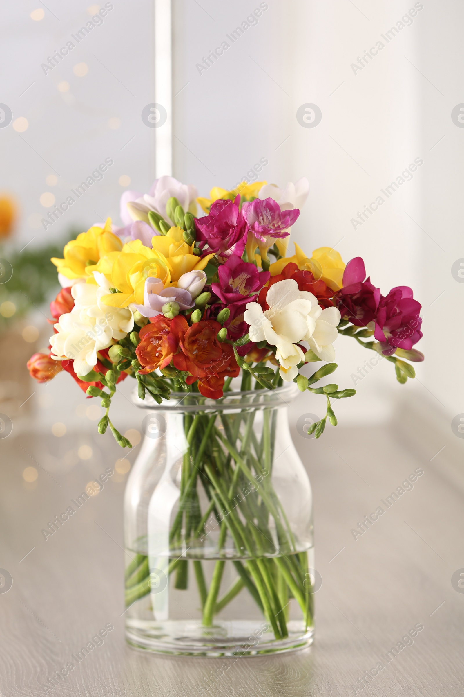 Photo of Beautiful spring bright freesia flowers in vase on table