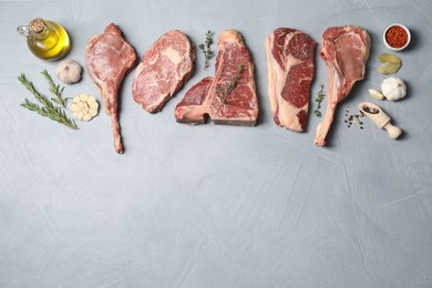 Photo of Fresh raw beef cuts, spices and oil on light grey textured table, flat lay. Space for text