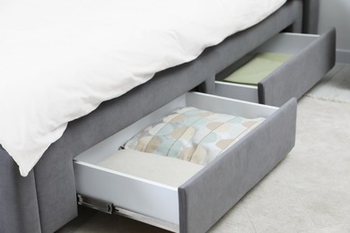 Storage drawers with bedding under modern bed in room