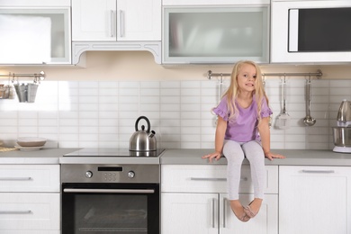 Cute little girl near oven in kitchen